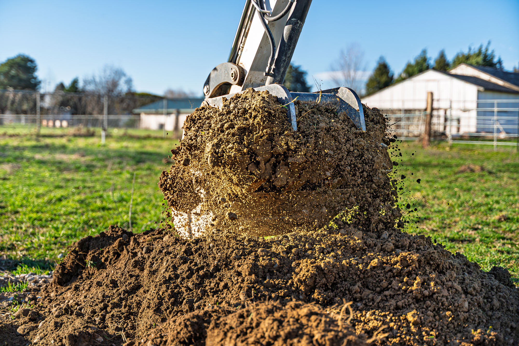 Excavator digging soil in a field.