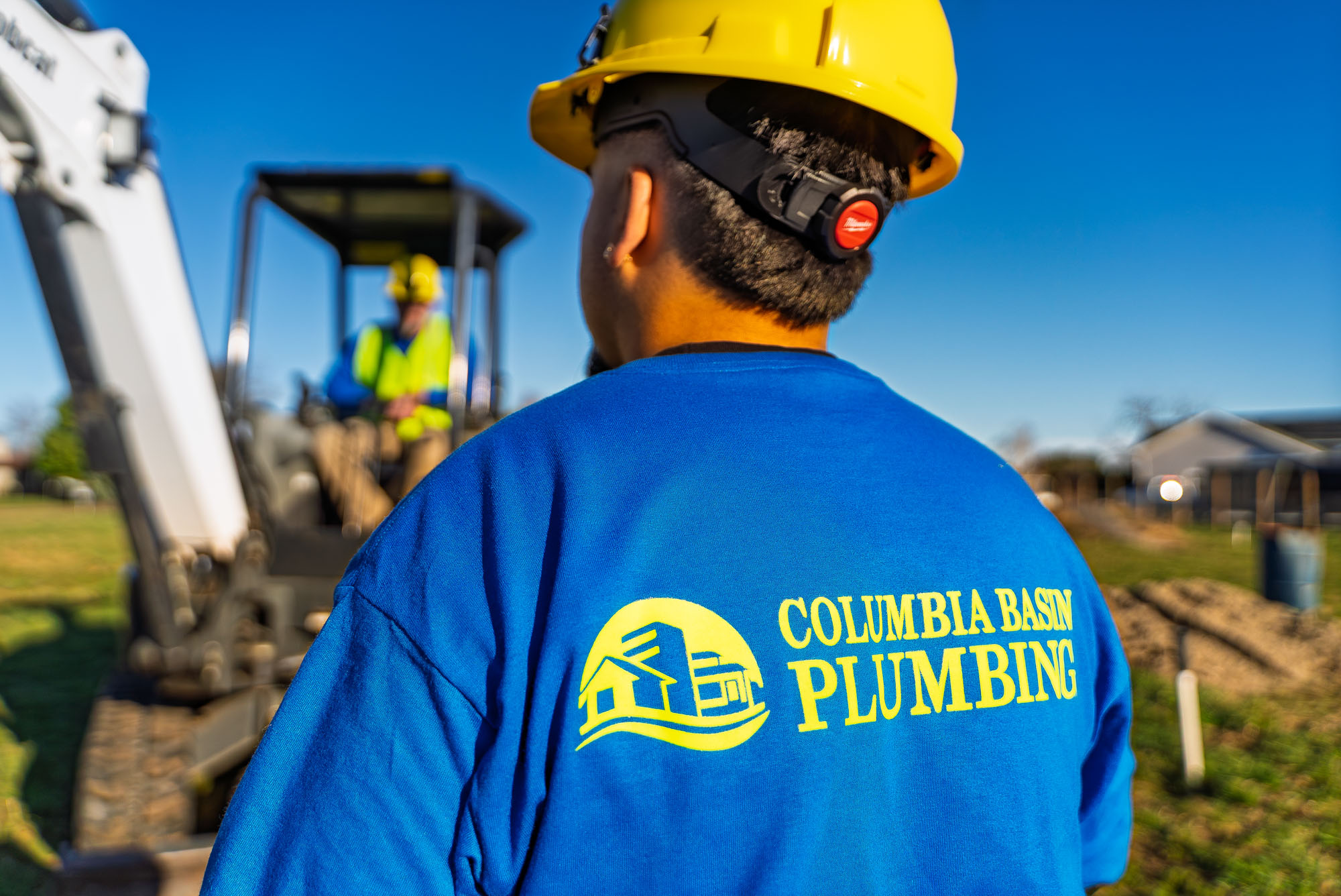 Plumbers working at construction site, wearing uniforms.