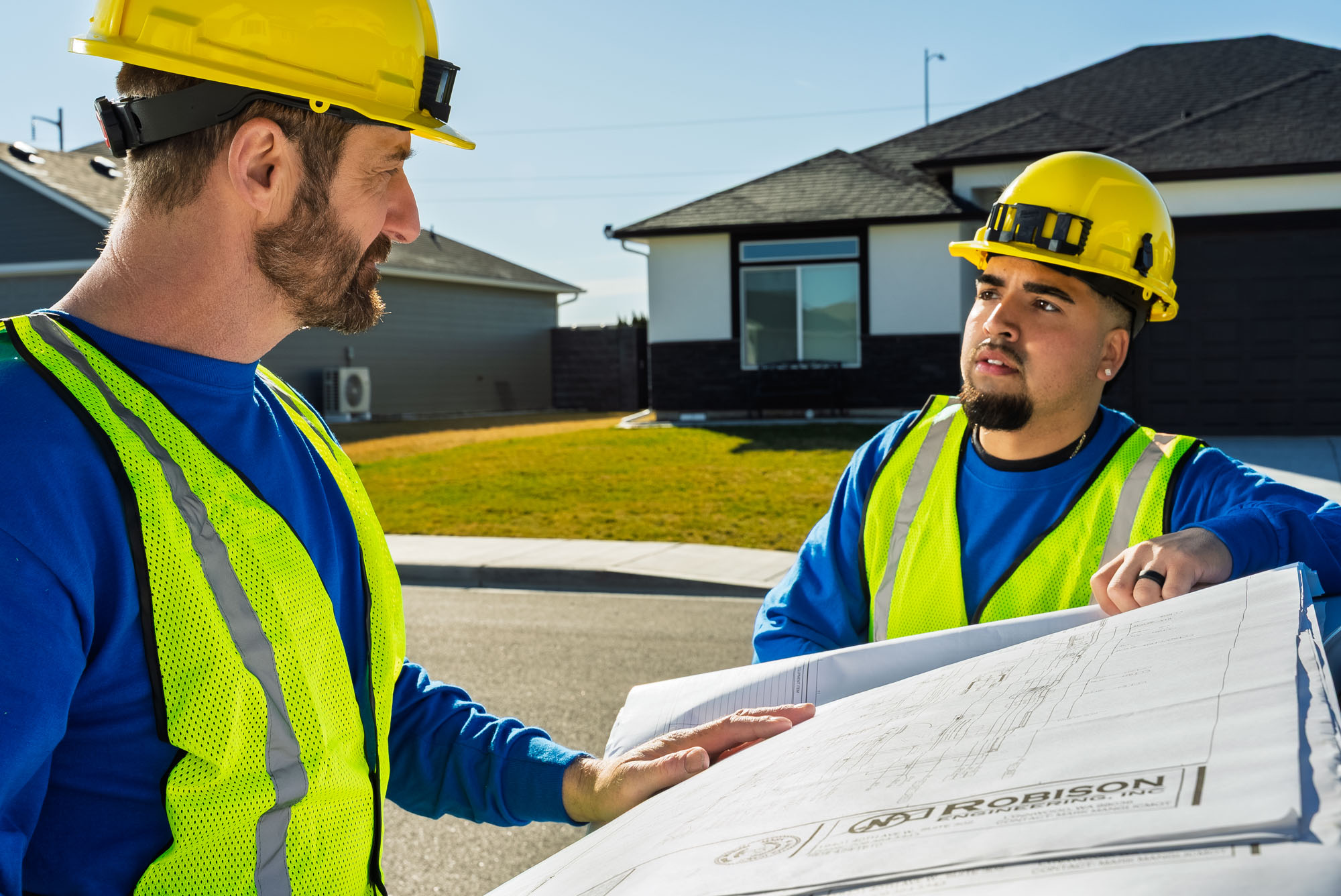 Construction workers reviewing building plans outdoors.
