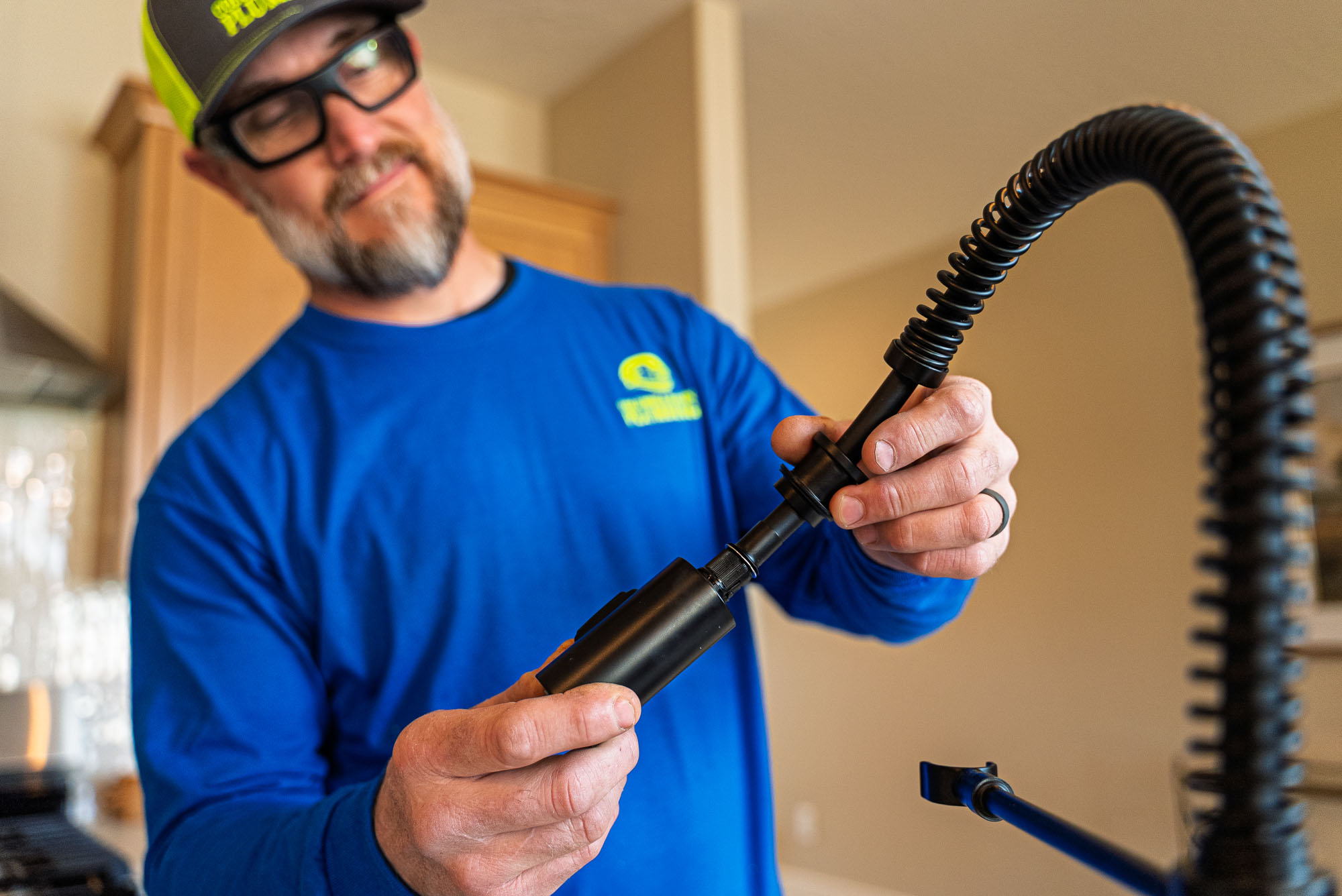 Man repairing kitchen faucet with tools.