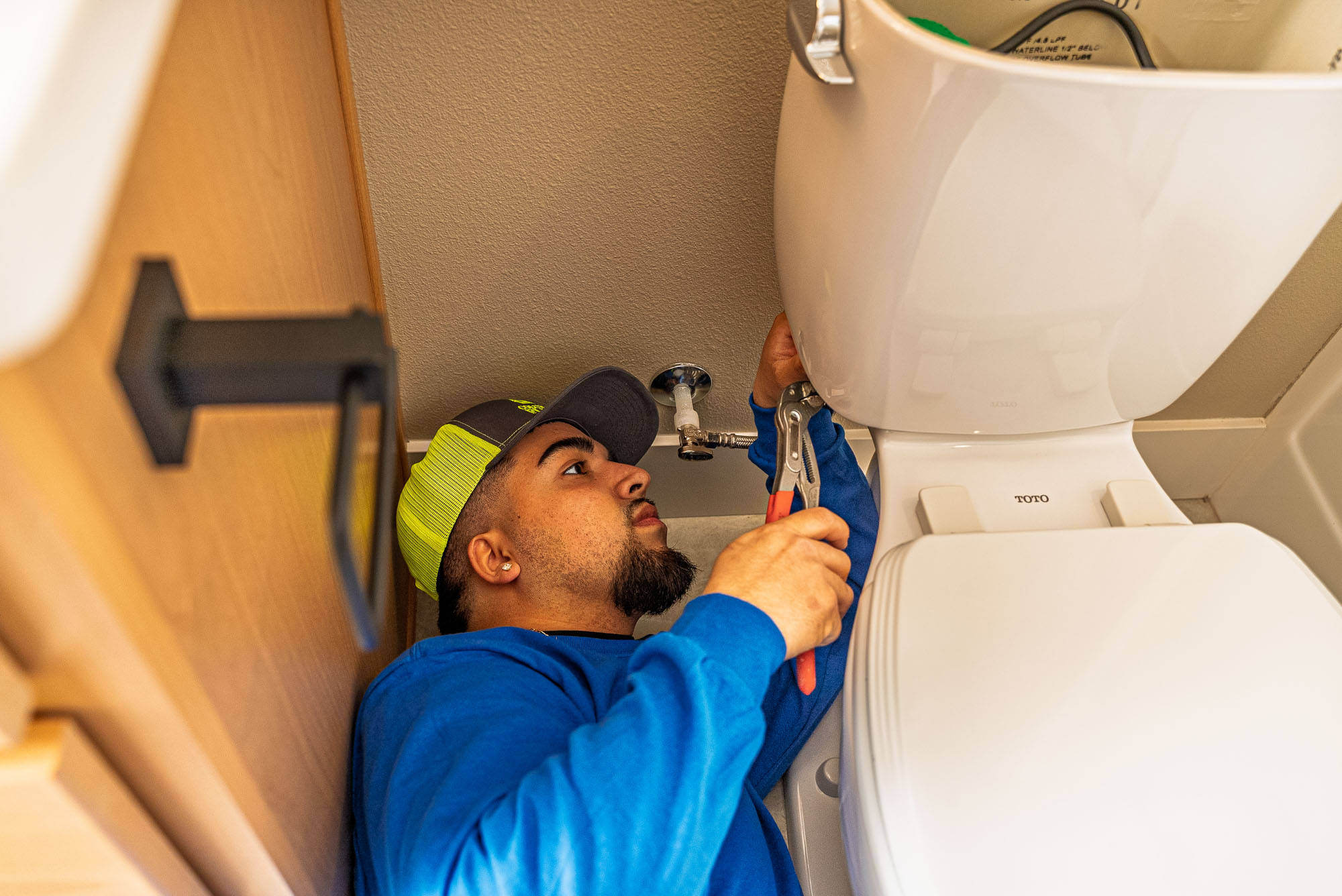 Plumber repairing toilet with wrench