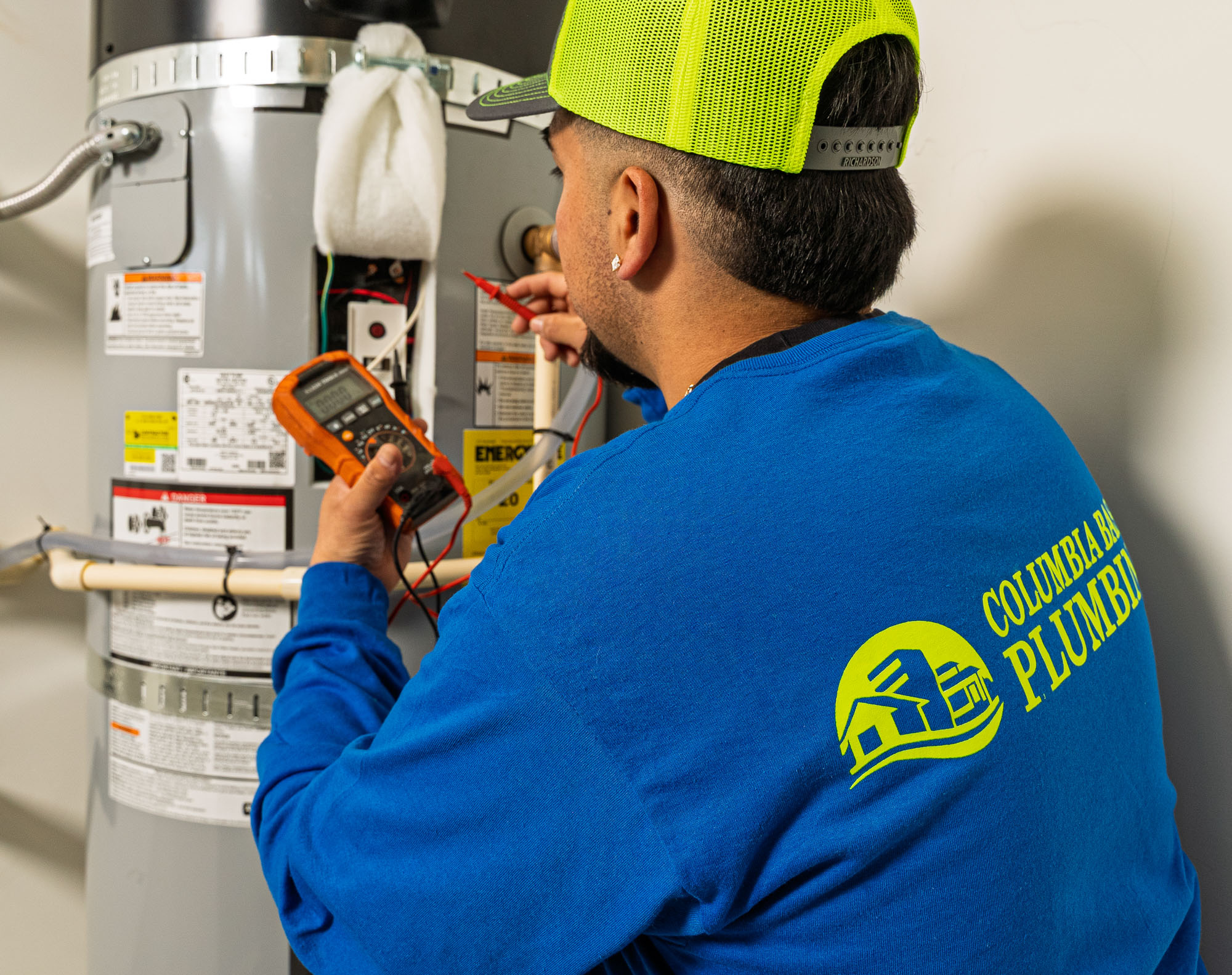 Plumber repairing water heater using tools.